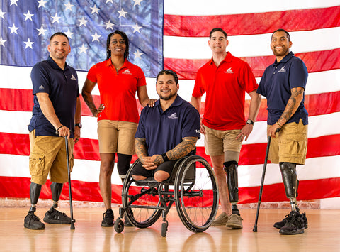 Five individuals with disabilities, including a person in a wheelchair, standing in front of an American flag.