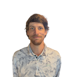 A man with short brown hair and a light beard wearing a light gray and white camouflage patterned zip-up shirt, shown against a plain white background.