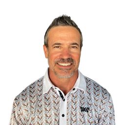 A smiling man with short graying hair wearing a white collared polo shirt with a brown and gray geometric pattern and a black PXF logo on the chest, set against a plain white background.