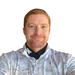A man with short reddish-brown hair and a light beard wearing a light gray and white camouflage patterned cycling jersey over a black collared shirt. The brand logo 'TXF' is visible on the chest of the jersey and on the collar.