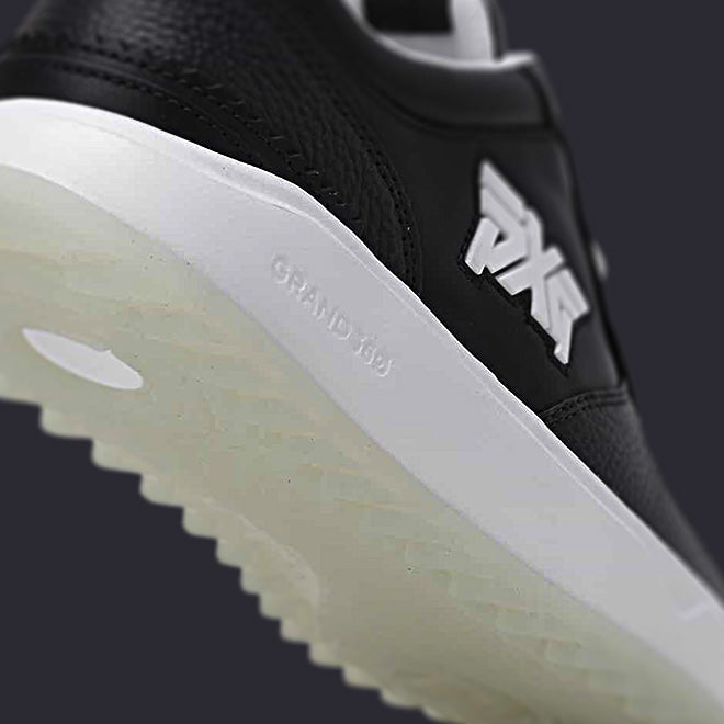 Close-up of a black and white sneaker with a brand logo on a dark background