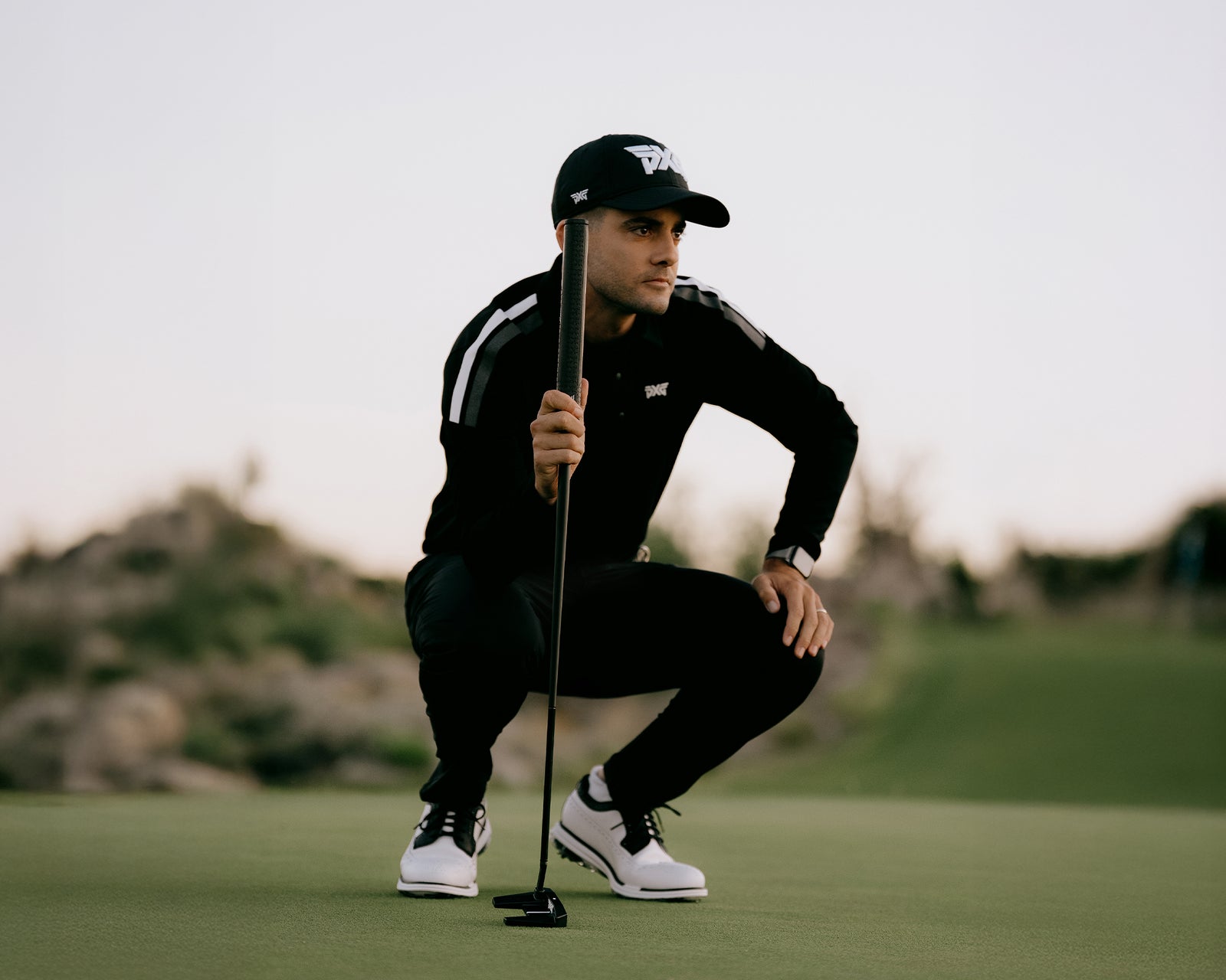Golfer in black outfit and cap on a golf course