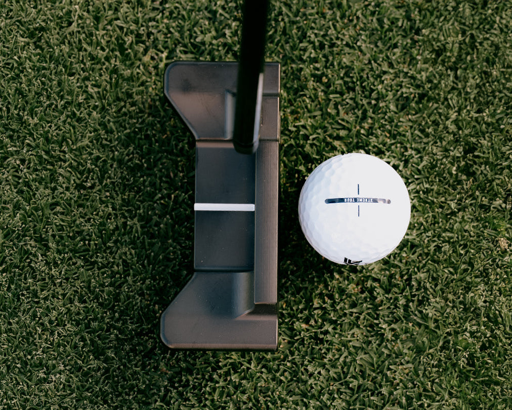 Golf putter and ball on a green grass surface