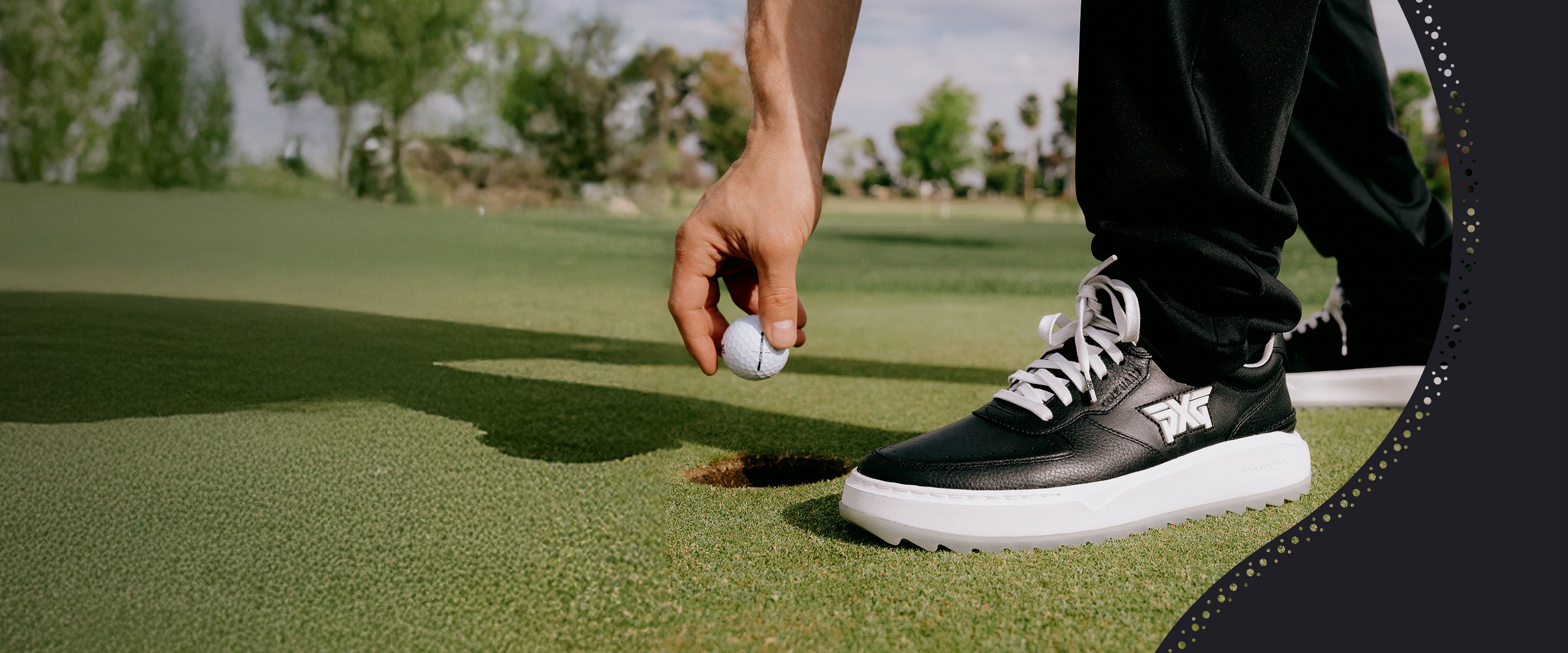Person on a golf course holding a golf ball with black shoes and white socks.