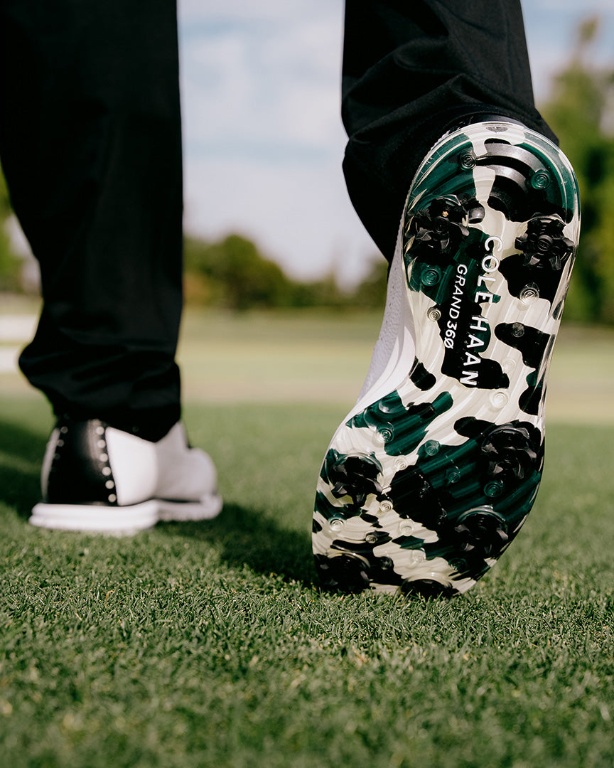 Golf shoes with a cow print sole on grass