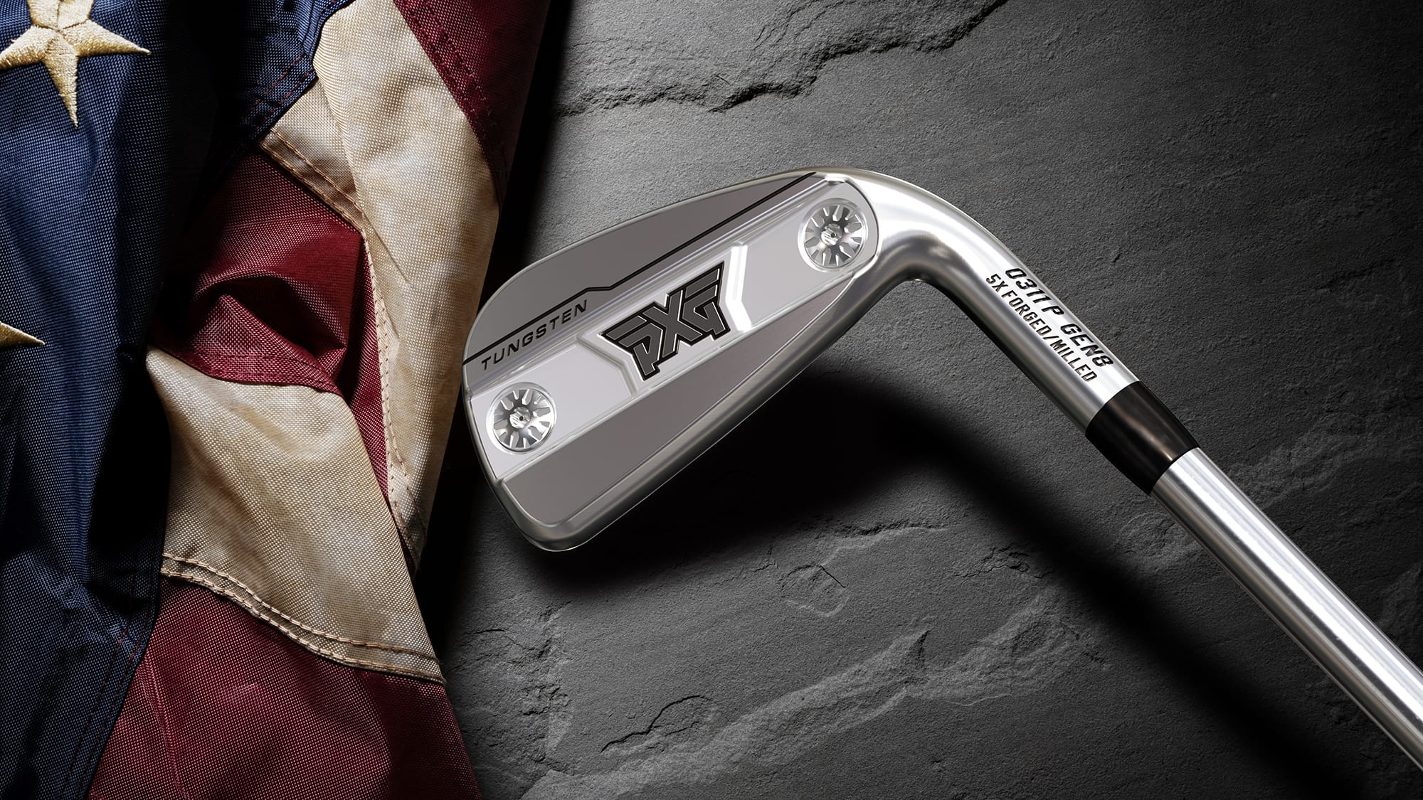 A close-up of a PXG iron golf club resting against a dark textured slate surface next to a draped American flag.