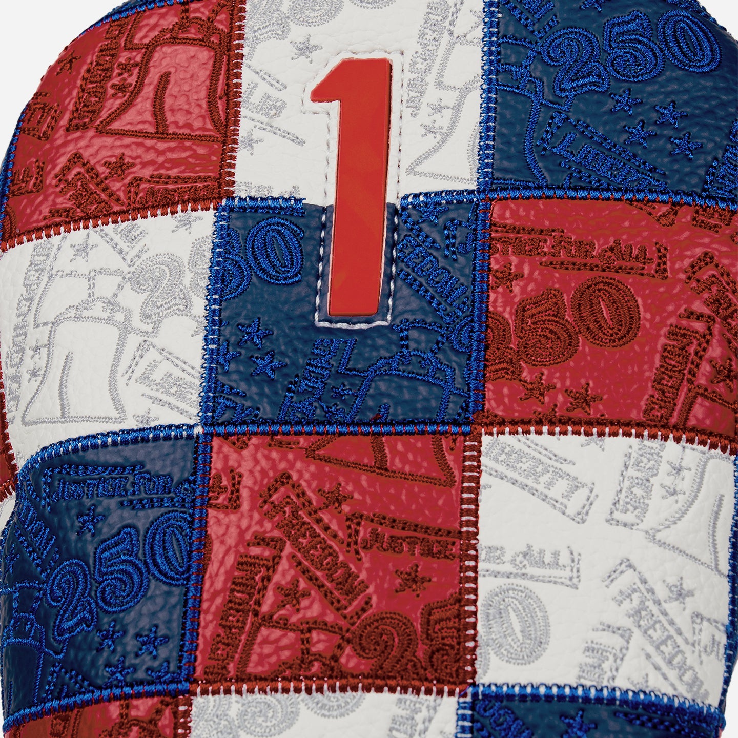 Driver headcover with patchwork colors of blue, white, and red and a red 1 on a white background