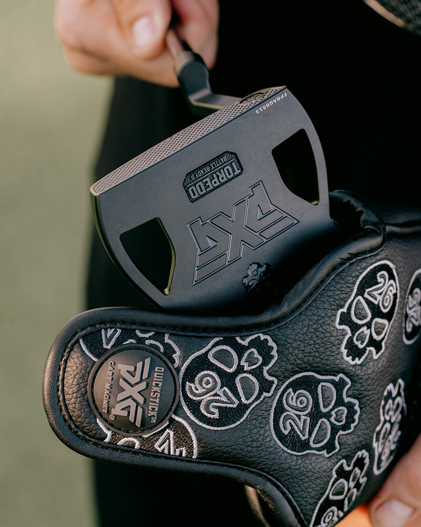 Close-up of a black putter head with branding and design details, held by a person.