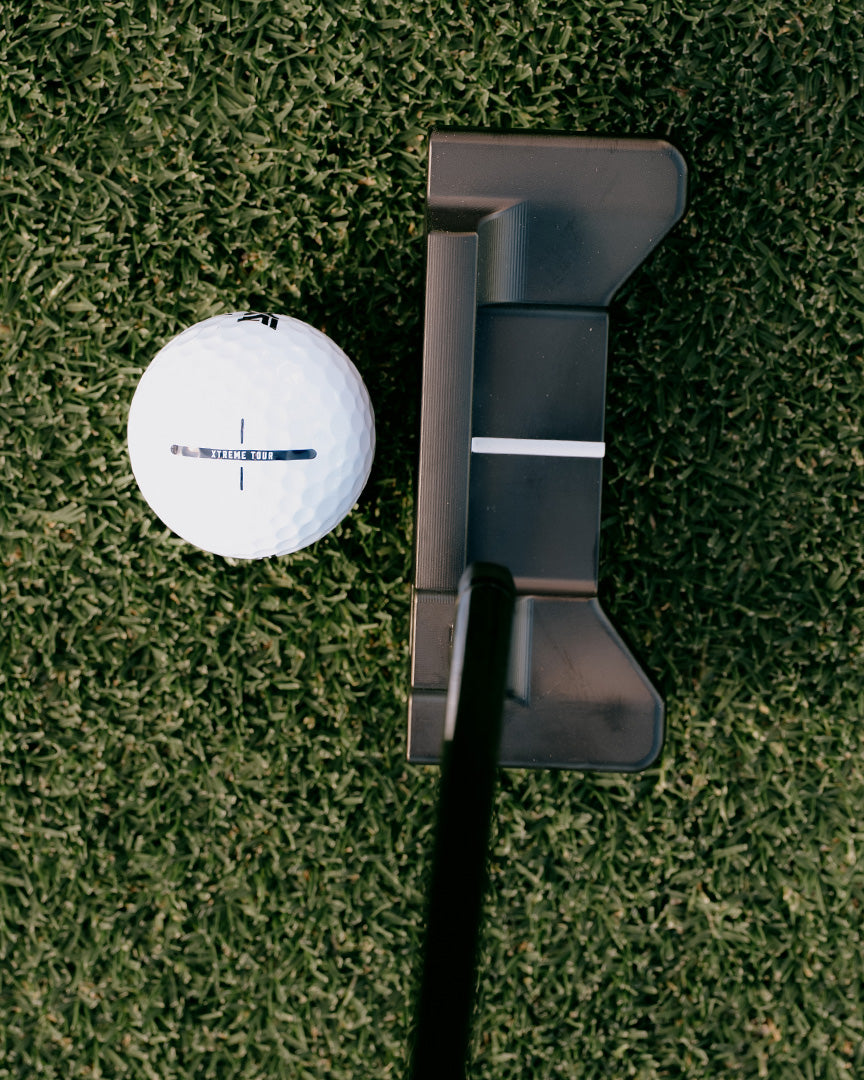Golf ball and putter on a green grass surface