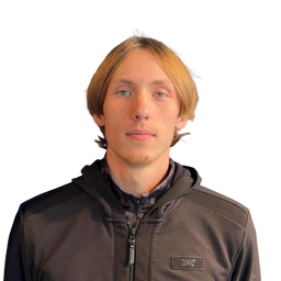 A man with light brown hair and blue eyes wearing a dark brown AXAT zip-up hoodie over a dark shirt, photographed against a solid white background.