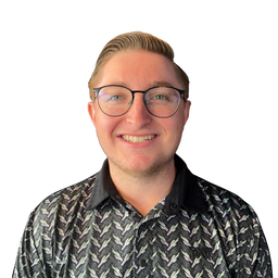 A smiling man with glasses and styled blond hair, wearing a black button-up shirt with a white and gray chevron pattern, isolated on a white background.