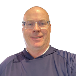 A close-up portrait of a bald man wearing clear-framed eyeglasses and a dark navy blue hooded shirt, set against a plain white background.