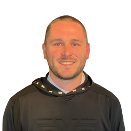 A smiling man with a shaved head and light beard, wearing a black athletic hoodie with a visible 'EYE' logo on the chest, photographed against a plain white background.