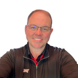 A smiling man with glasses wearing a dark brown zip-up athletic jacket over a red and black collared shirt, photographed against a plain white background.