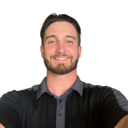 A smiling man with a beard and short dark hair wearing a black short-sleeve polo shirt with gray side panels and a gray collar, photographed against a plain white background.