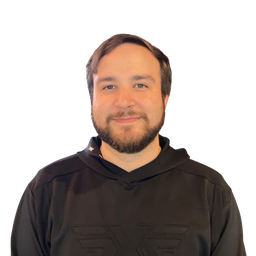 A man with a beard wearing a black hooded sweatshirt, photographed against a plain white background.