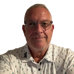 A close-up portrait of a man with short gray hair and glasses, wearing a white polo shirt with a small green pattern, set against a plain white background.