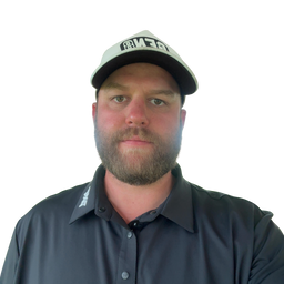 A man wearing a black and white cap with a stylized logo and a dark gray button-down shirt, photographed against a solid white background.