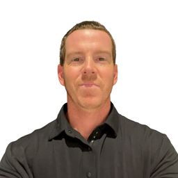 A man with short brown hair wearing a dark gray button-down shirt, shown from the chest up against a plain white background.