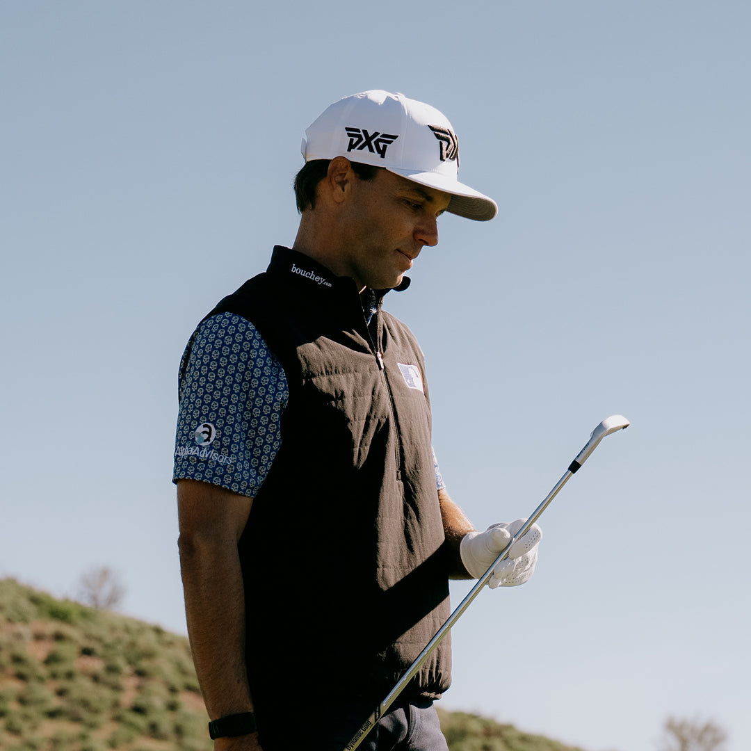 PGA Tour Pro Eric Cole wearing PXG Golf Hat holding a golf club on a golf course