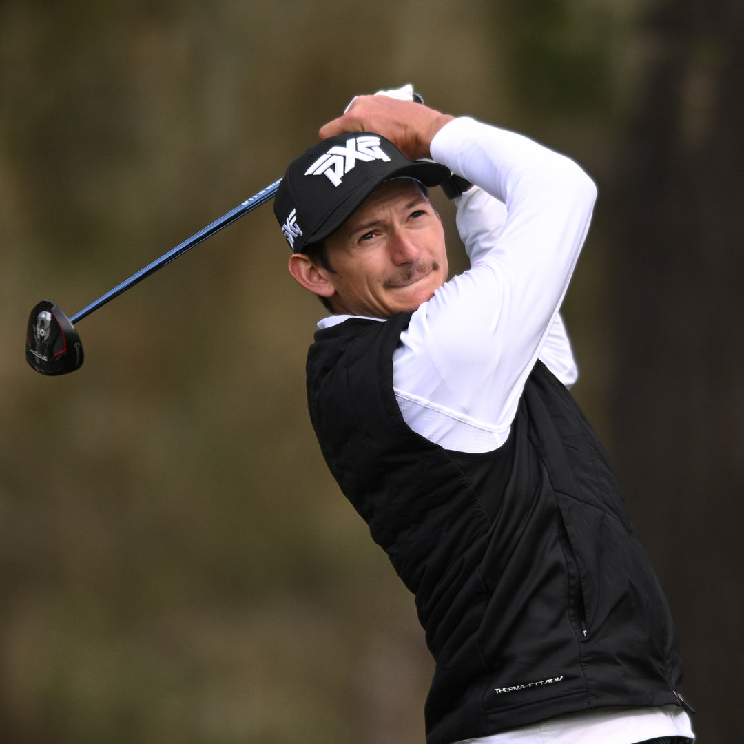 Tour Pro Garrett Reband wearing a PXG hat swinging a golf club on a golf course.