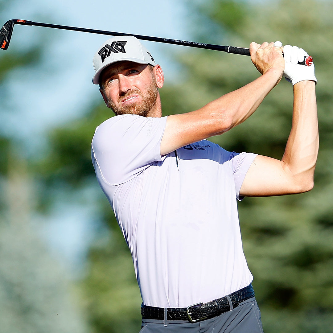 Pro Kevin Dougherty wearing a PXG Hat and swinging a golf club on a golf course.