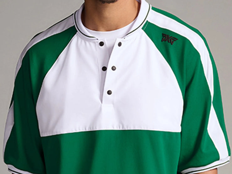 A close-up of a men's short-sleeve raglan henley shirt in green and white, featuring a three-button placket and a small black embroidered logo on the left chest.